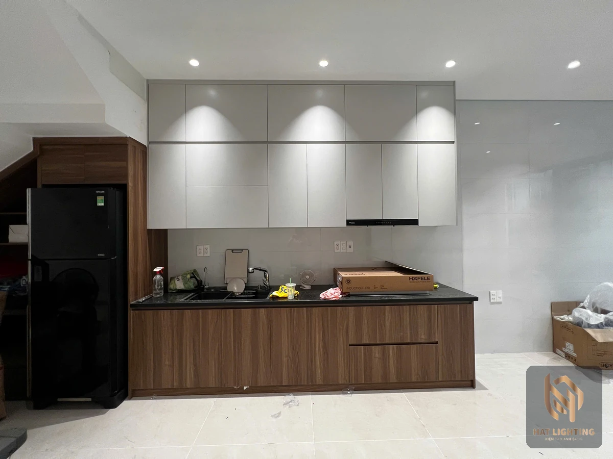 Bếp nhà phố với đèn âm trần và tủ bếp ốp gỗ