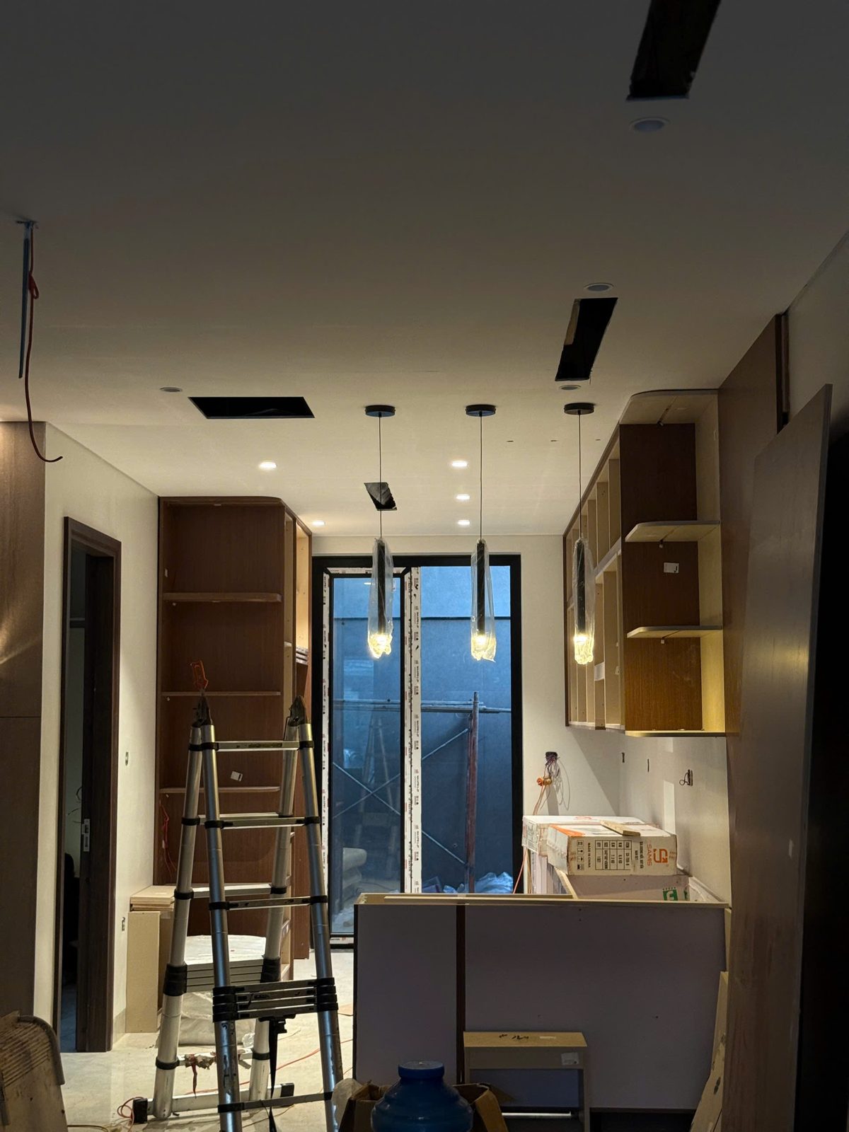 Đảo bếp với ba đèn thả và đèn âm trần đã lên đèn trong công trình HAT Lighting đang hoàn thiện