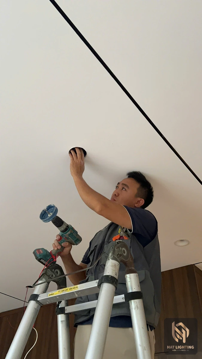 Kỹ thuật viên khoan và lắp đèn âm trần thạch cao theo bản vẽ